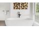 Modern soaking tub with geometric art piece above and black modern fixtures at 1665 S Fillmore St, Denver, CO 80210