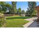 Spacious backyard with lush green lawn, mature trees, shed and patio area at 215 Sunland St, Louisville, CO 80027