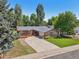Charming single-story home featuring a well-manicured lawn, mature trees, and a cozy front porch at 215 Sunland St, Louisville, CO 80027