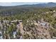 Wide aerial view showcasing a home, additional structure, and outbuilding surrounded by a dense forest at 31911 Warrens Rd, Golden, CO 80403