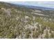 Expansive aerial view of a forested property featuring a home, outbuilding and mountainous terrain at 31911 Warrens Rd, Golden, CO 80403