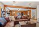 Spacious living room with exposed beam and wood paneling with a large leather couch and unique decor at 31911 Warrens Rd, Golden, CO 80403