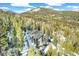 Aerial exterior view of a mountain house surrounded by evergreen trees and snow at 1758 Sinton Rd, Evergreen, CO 80439