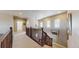 Upstairs hallway with wood railing, neutral carpeting, and natural light from shuttered windows at 8605 S Zante Ct, Aurora, CO 80016