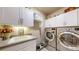 Functional laundry room with modern appliances, storage cabinets, and a utility sink at 8605 S Zante Ct, Aurora, CO 80016
