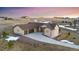 Beautifully designed beige home with a three-car garage, set against a backdrop of rolling hills and a picturesque sunset at 20201 Royal Troon Dr, Monument, CO 80132