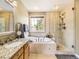 Luxurious bathroom featuring a soaking tub, walk-in shower, granite counters, and vanity mirror at 9625 S Hackberry St, Highlands Ranch, CO 80129