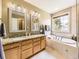 Bright main bathroom with double vanity, granite countertops, a soaking tub, and natural light at 9625 S Hackberry St, Highlands Ranch, CO 80129