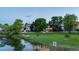 Expansive backyard with a lush green lawn, mature trees, and views of the tranquil pond at 6266 Holman St, Arvada, CO 80004