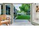 Backyard view through open door features a lush green lawn, mature trees, and a charming white fence at 6266 Holman St, Arvada, CO 80004