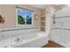 Bathroom featuring a soaking tub under a window and a glass-enclosed shower with built-in shelves at 6266 Holman St, Arvada, CO 80004