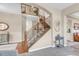 Open staircase with wooden banister, neutral carpeting, and adjacent living spaces with hardwood floors at 6266 Holman St, Arvada, CO 80004