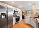 Bright kitchen features stainless steel appliances, white cabinetry, and an open layout with views to the dining area and living room at 8403 S Miller Ct, Littleton, CO 80127