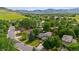 Stunning aerial view of a neighborhood with lush trees, green lawns, and mountain views at 5971 Windy St, Golden, CO 80403