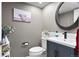 Charming half bathroom featuring updated fixtures, navy blue vanity, stylish mirror and neutral paint at 8288 W Chestnut Ave, Littleton, CO 80128