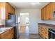 Open kitchen featuring stainless steel refrigerator, wooden cabinets, and view to living room at 10454 Grant Dr, Northglenn, CO 80233