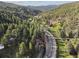 Stunning aerial view of the house nestled in a lush green valley with mountain views and a winding road at 27383 Highway 74, Evergreen, CO 80439