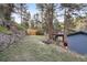 Grassy backyard with stone retaining wall, wooden fence, and covered patio area at 27383 Highway 74, Evergreen, CO 80439