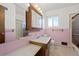 Vintage bathroom featuring pink tile, a built-in medicine cabinet and a shower-tub combination with a sliding glass door at 343 Melody Dr, Northglenn, CO 80260