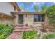Welcoming brick home featuring a covered porch, mature landscaping, and an inviting front door at 10165 W Iowa Ave, Lakewood, CO 80232