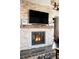 Close up of stone fireplace with a wood beam mantle and a flat screen television above at 1275 Washington Ave, Golden, CO 80401