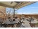 This is a covered patio with an outdoor dining set and a fire pit in the background at 13475 Spruce St, Thornton, CO 80602