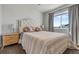 A serene bedroom with a striped bedspread, decorative pillows, a light wood nightstand and soft window light at 6852 S Algonquian Ct, Aurora, CO 80016