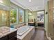 Bright bathroom with tiled walk-in shower, soaking tub, dual vanity with granite countertops, and views of the outdoors at 15264 W La Salle Ave, Lakewood, CO 80228