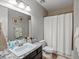Updated bathroom with granite vanity, framed mirror, tile flooring, and combination tub and shower with white shower curtain at 15264 W La Salle Ave, Lakewood, CO 80228