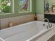 Close-up view of soaking tub featuring designer plumbing fixtures, tile surround, and exterior views through dual windows at 15264 W La Salle Ave, Lakewood, CO 80228