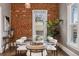 Stylish dining room with exposed brick wall and a modern glass-top table with seating for six at 321 S Emerson St, Denver, CO 80209