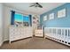 Bedroom with blue accent wall, crib, white dresser, and natural light at 23413 E Dorado Pl # A, Aurora, CO 80016