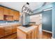 Open kitchen featuring tile countertops, wooden cabinets, and a center island with cooktop at 3921 S Acoma St, Englewood, CO 80110