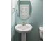 Powder room featuring pedestal sink, oval mirror and pale blue walls, with toilet in the background at 8739 E 23Rd Ave, Denver, CO 80238