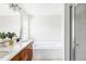 Bright primary bath with double vanity, soaking tub and glass enclosed shower in a modern style at 8739 E 23Rd Ave, Denver, CO 80238