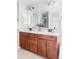 Bathroom vanity with double sinks, warm wood cabinets, quartz countertop, and large mirror at 8739 E 23Rd Ave, Denver, CO 80238
