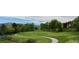 Wide view of a lush golf course and cart path amid a neighborhood community with trees and mountains at 16179 W 70Th Pl, Arvada, CO 80007
