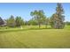 Scenic view of the community golf course with mature trees and meticulously maintained green at 16179 W 70Th Pl, Arvada, CO 80007