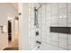 Bright shower featuring stylish vertical white tile with black fixtures and a built-in shelf at 16179 W 70Th Pl, Arvada, CO 80007