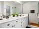 Bathroom with double sinks, white cabinets, subway tile shower, and hardwood floors at 1063 Roslyn Ct, Denver, CO 80230