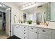 Bathroom with double sinks, white cabinets, subway tile shower, and hardwood floors at 1063 Roslyn Ct, Denver, CO 80230