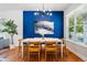 Stylish dining room featuring a blue accent wall, a modern chandelier, and hardwood flooring at 1063 Roslyn Ct, Denver, CO 80230