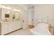 Well-lit bathroom featuring double sinks, a soaking tub, and access to another room at 729 E 10Th Ave, Denver, CO 80203