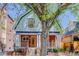 Charming two-story home with brick stairs, pillars, wooden front door, and a large tree in the front yard at 729 E 10Th Ave, Denver, CO 80203