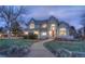 Inviting two-story home at dusk, showcasing a lit brick pathway and lush front yard at 8 Mountain Willow Dr, Littleton, CO 80127