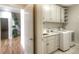 Well-lit laundry room featuring white cabinetry, a sink, countertop space, and modern washer and dryer units at 8 Mountain Willow Dr, Littleton, CO 80127