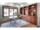 Home office with custom built-in shelving, a modern desk, a comfortable chair, and natural light from the windows at 8 Mountain Willow Dr, Littleton, CO 80127