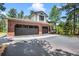 A beautiful home with a brick two-car garage and paved driveway surrounded by mature trees at 1240 Lone Scout Lookout, Monument, CO 80132