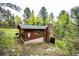 Exterior of a home nestled among mature trees featuring a stone chimney at 12346 Bear Haven Rd, Conifer, CO 80433