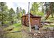 Home exterior surrounded by lush greenery with a stone chimney and outdoor seating at 12346 Bear Haven Rd, Conifer, CO 80433